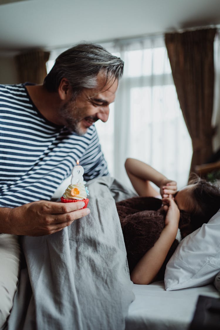 Father Waking Up His Daughter With A Birthday Cupcake 