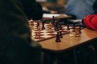Crop people playing chess in room