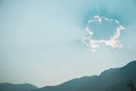 Sun shining through cloud over mountains