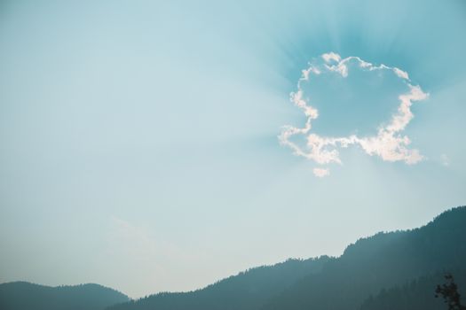 Sun shining through cloud over mountains