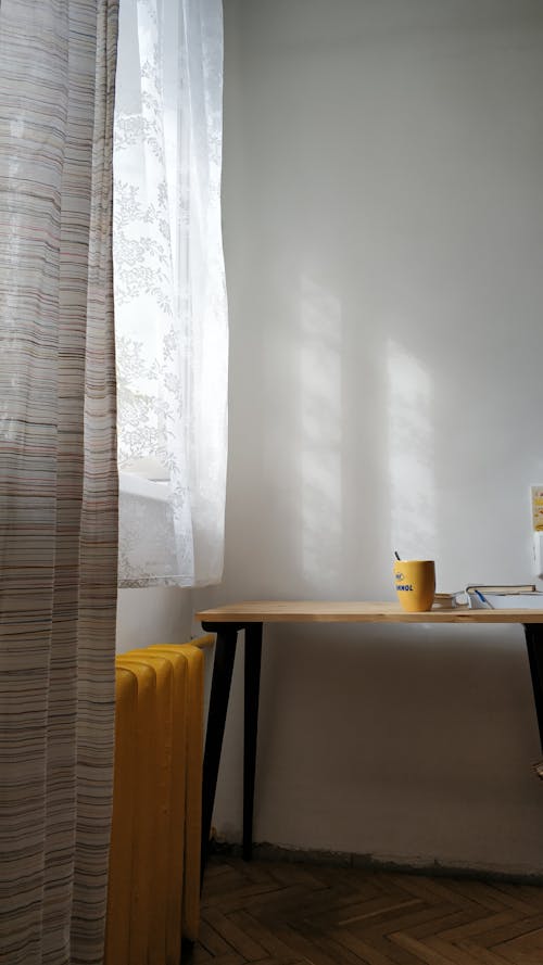 Yellow heating radiator and table against white wall