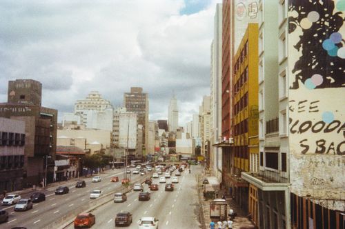 Free High angle view of a bustling city street with traffic and skyscrapers under cloudy skies. Stock Photo