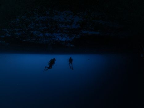 两名水肺潜水员探索深海的戏剧性轮廓，唤起了神秘与冒险感