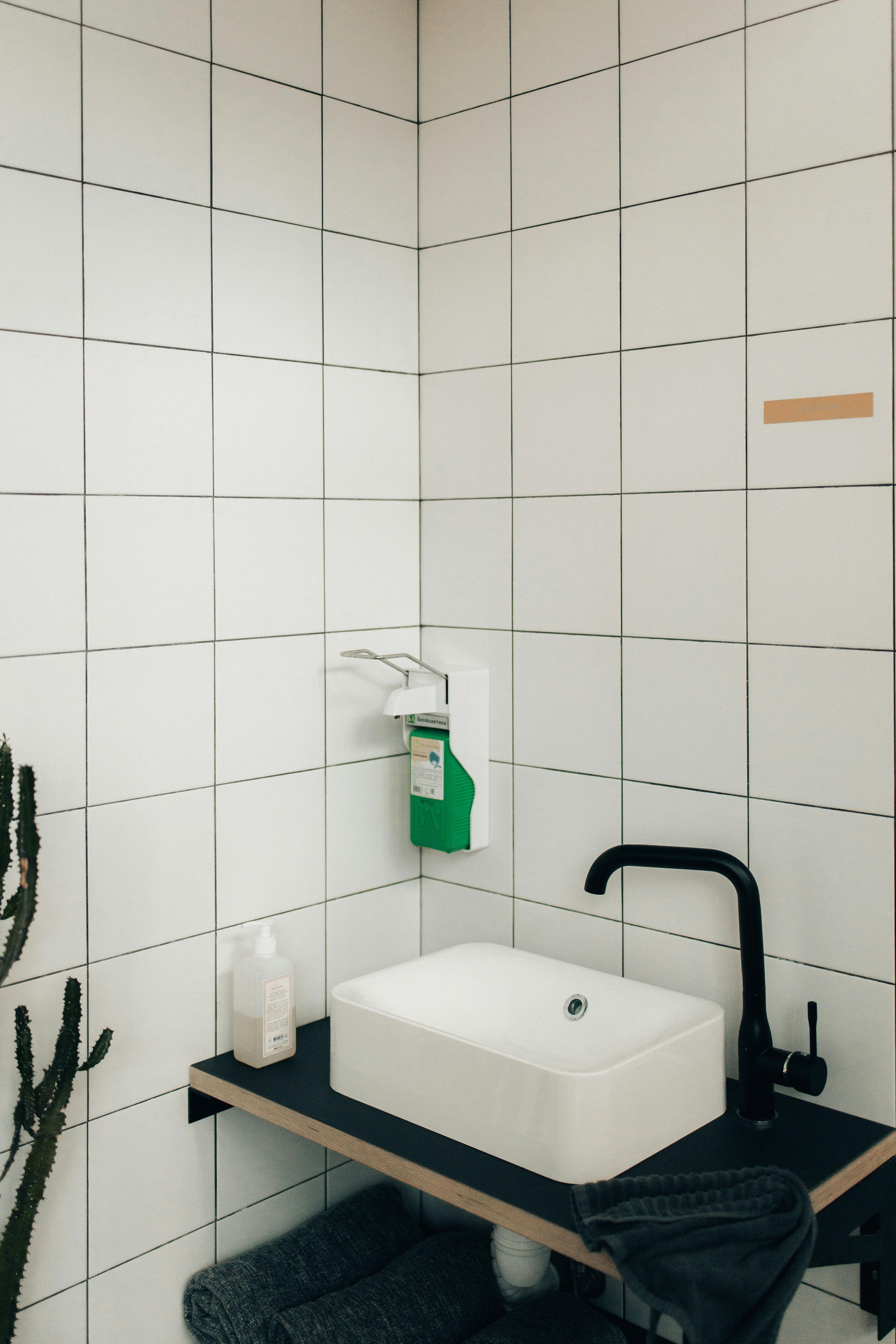 Free Modern bathroom showcasing sleek faucet and tiled walls in a minimalist design. Stock Photo