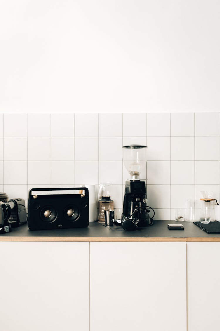 A Coffee Maker Beside Black Speaker On Kitchen Table Top