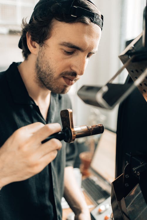 Free Close-up of Man Operating a Machine at a Coffee Roasting Factory Stock Photo