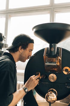 A man operates a coffee roasting machine inside a modern coffee house.