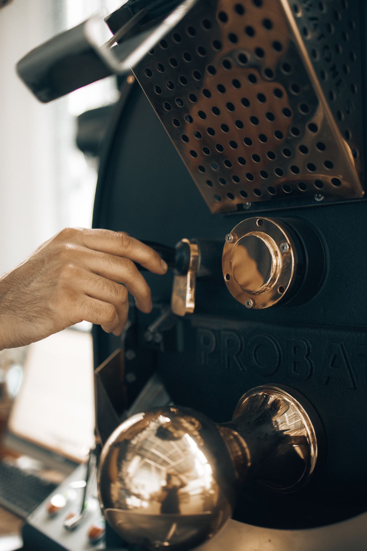 Hand adjusting settings on a professional coffee roaster, for illustration