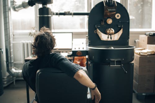 Free Man Operating a Machine at a Coffee Roasting Factory and Using a Computer  Stock Photo