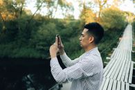 一名男子在桥上用智能手机拍摄自然风光
