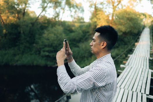 一名男子在桥上用智能手机拍摄自然风光
