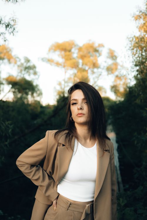 Free Stylish woman posing outdoors in a fashionable suit with natural backdrop. Stock Photo