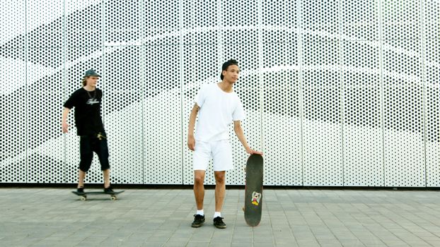 两名青少年在城市里享受着现代背景下的滑板活动