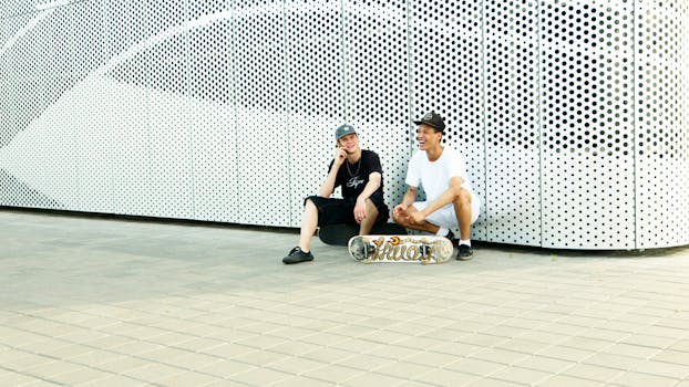 两名滑板爱好者坐在现代城市艺术墙旁休息