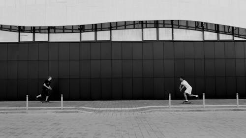 Grayscale Photo of Two Men using Skateboard