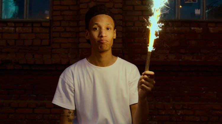 A Man In White Shirt Holding A Firework Candle