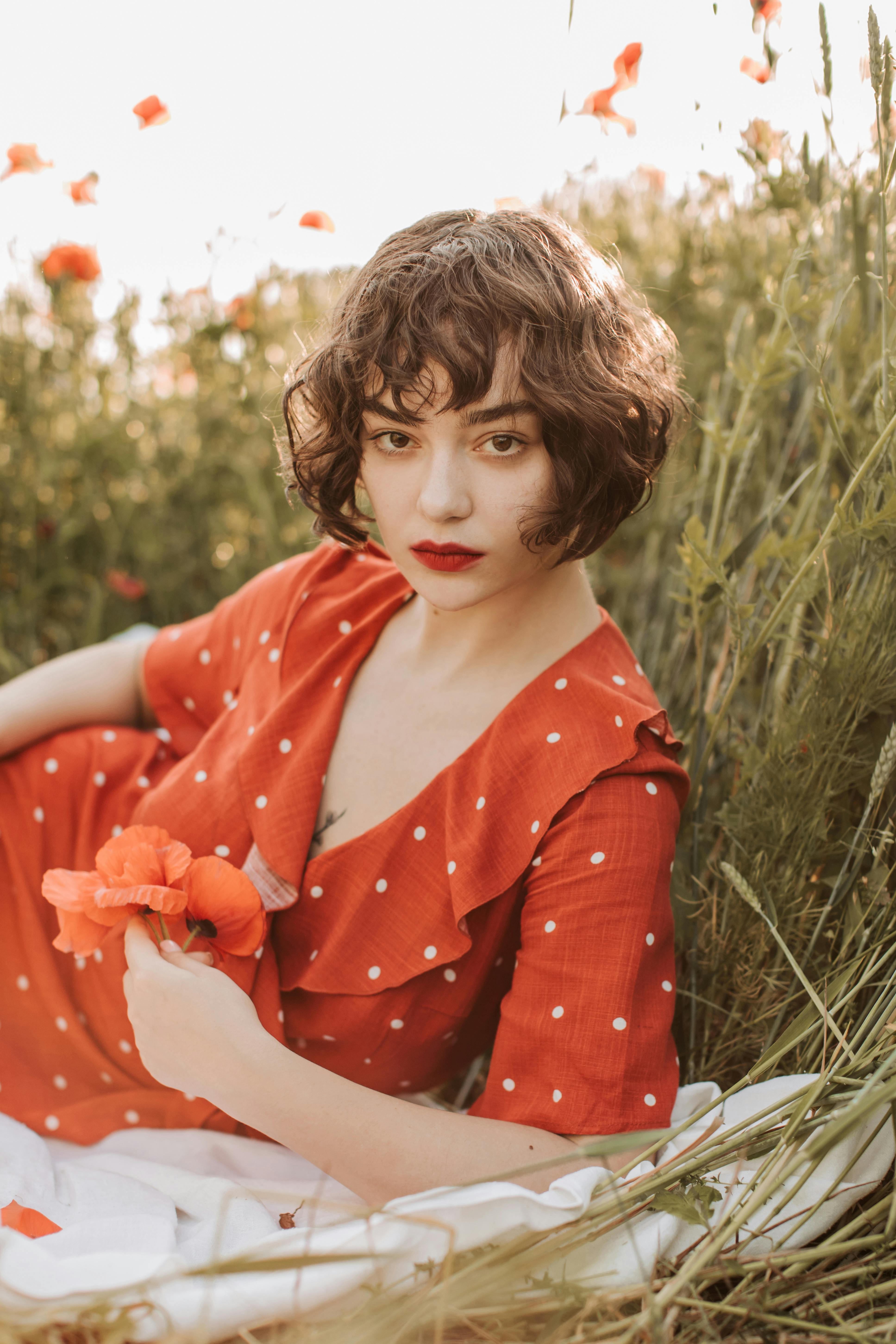 a woman in red dress holding a poppy flower