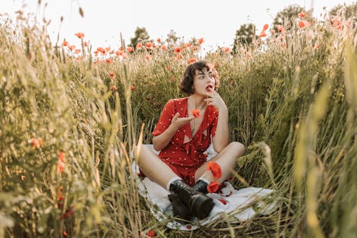 Woman in Red Polka Dot Dress Sitting on a Flower Field