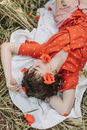 一位穿着红色连衣裙的女人安详地躺在罂粟花田里，展现出宁静与自然之美