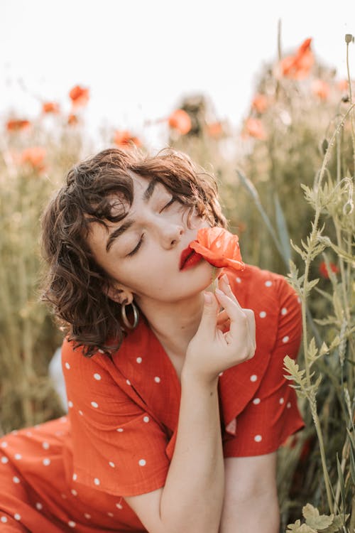 Free A Woman Holding a Poppy Flower While Eyes Closed Stock Photo