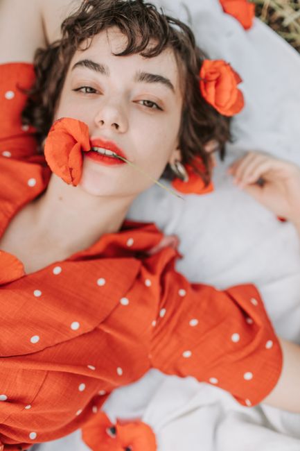 A graceful woman in a red dress adorned with poppy flowers, exuding elegance and beauty.