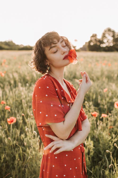 Woman in Red Polka Dots Dress Holding Red Flower