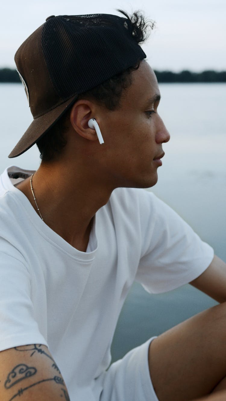 Man In White Shirt And Cap Wearing A Wireless Earpods