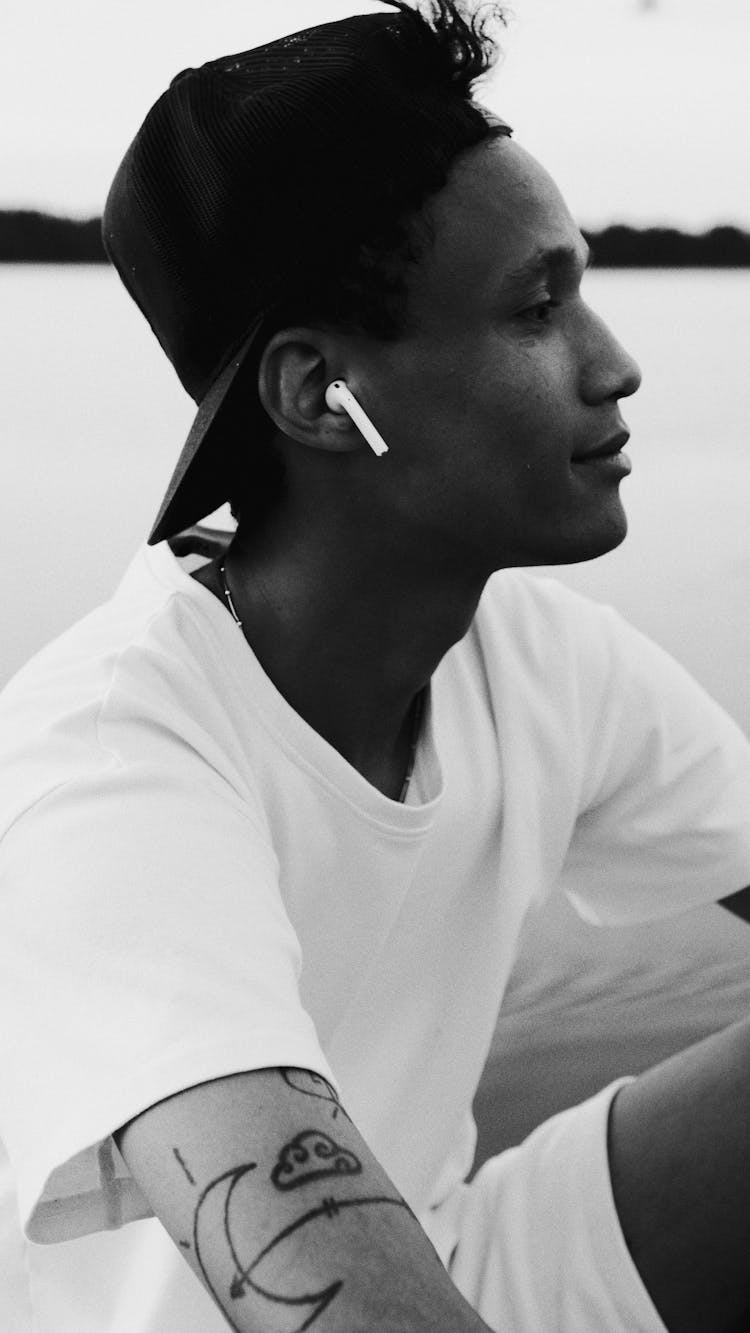 Grayscale Photo Of A Man With White Airpods 