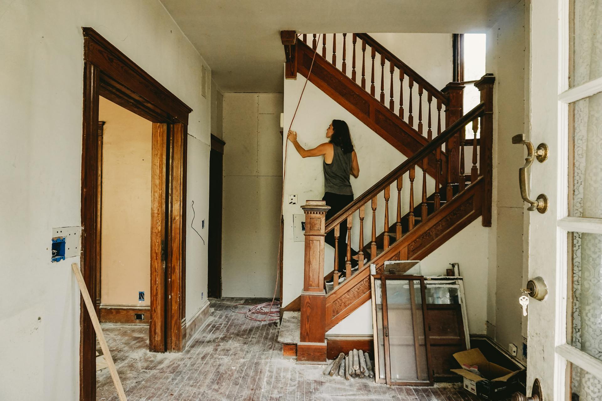 A woman working on home renovation featuring a wooden staircase.