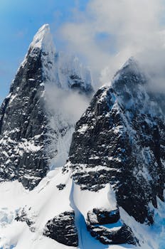 Majestic snowy peaks with fog, showcasing a dramatic winter landscape.