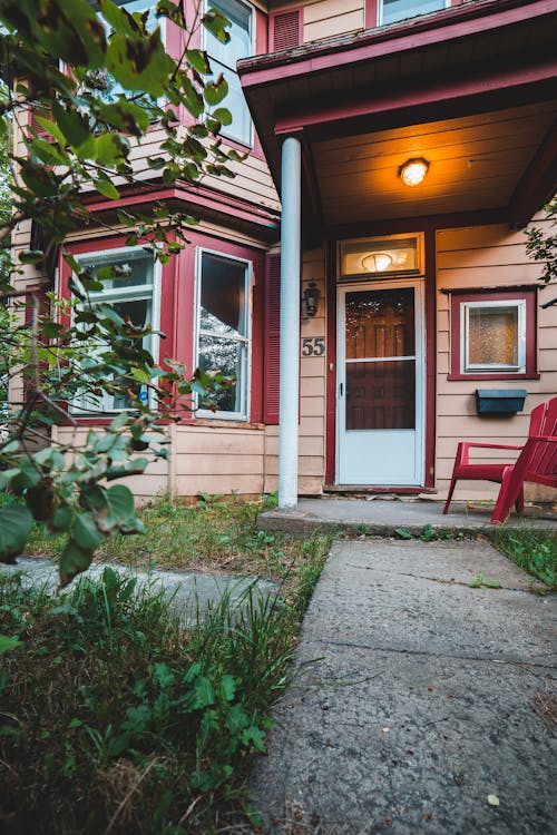 Low angle exterior of aged cozy residential cottage with geometric windows and green garden in yard