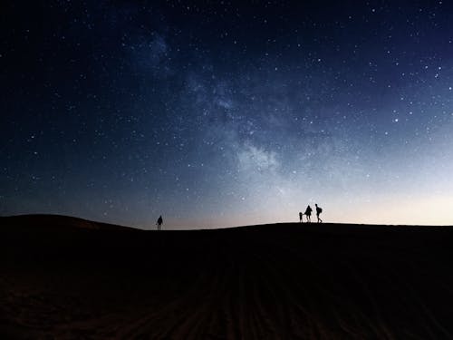 Silhouette of People Walking Outdoors under the Starry Sky