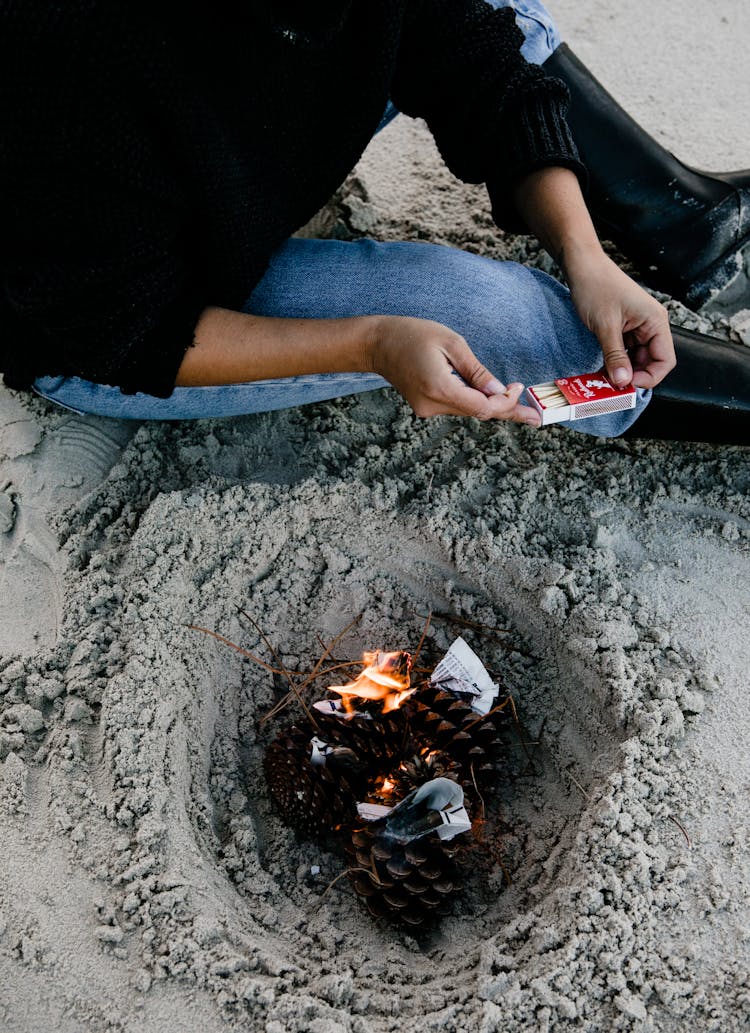 Person Sitting On Gray Sand Holding A Matchbox 