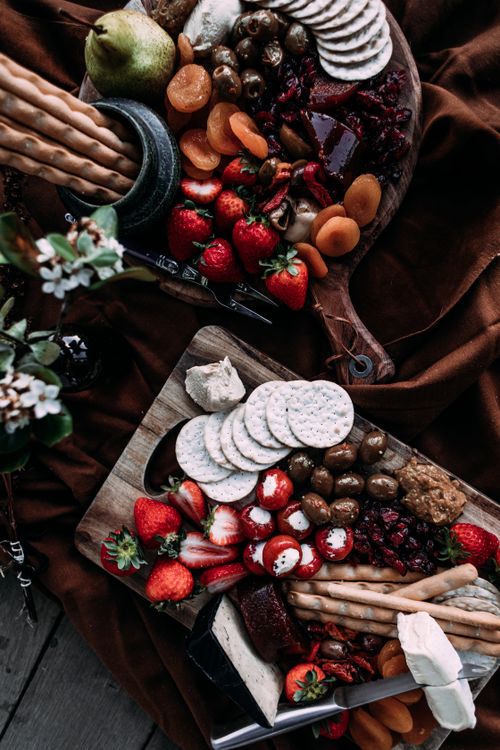 Free Top view of a rustic cheese platter featuring fruits, olives, and crackers. Stock Photo