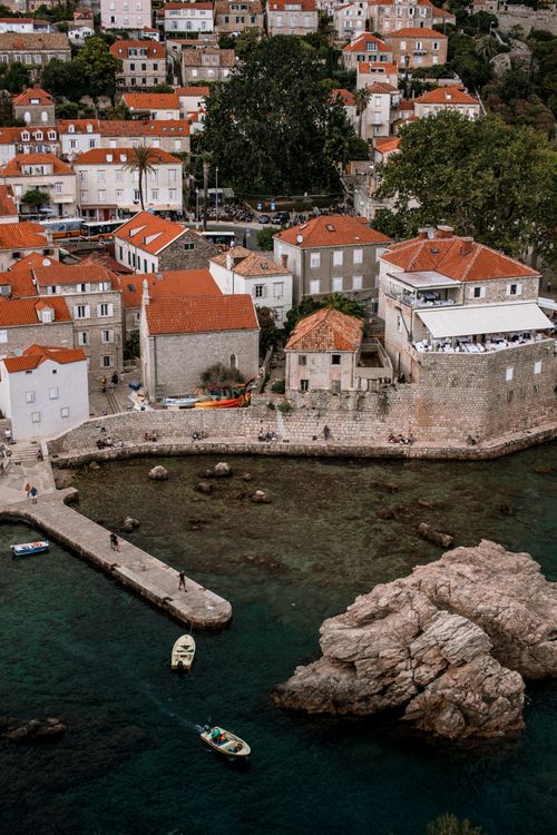 Free Charming coastal town with red roofs, rocky shoreline, and clear waters. Stock Photo