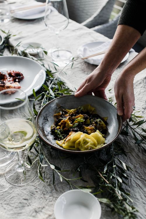 Free Elegant dining setup featuring a fresh pasta dish paired with a glass of white wine, perfect for gourmet meals. Stock Photo