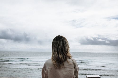 Woman in Brown Jacket In Front of Beach 