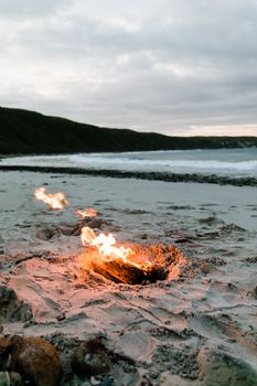 黄昏时分，宁静的海滩上，靠近海浪的沙滩燃着一小堆篝火