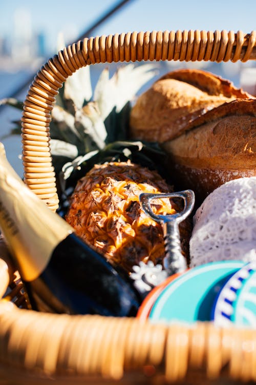 Closeup of wicker basket full of food with fresh ripe fruits and bottle of alcoholic drink