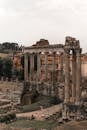 Ruins of ancient stone building with columns near green lawn in European city