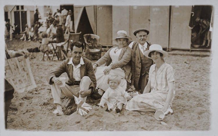 Photo Of Family Sitting On Beach Sand