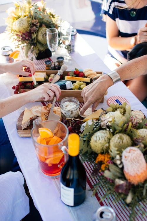 Free Crop anonymous people sitting at table and drinking wine and eating fruits and food Stock Photo