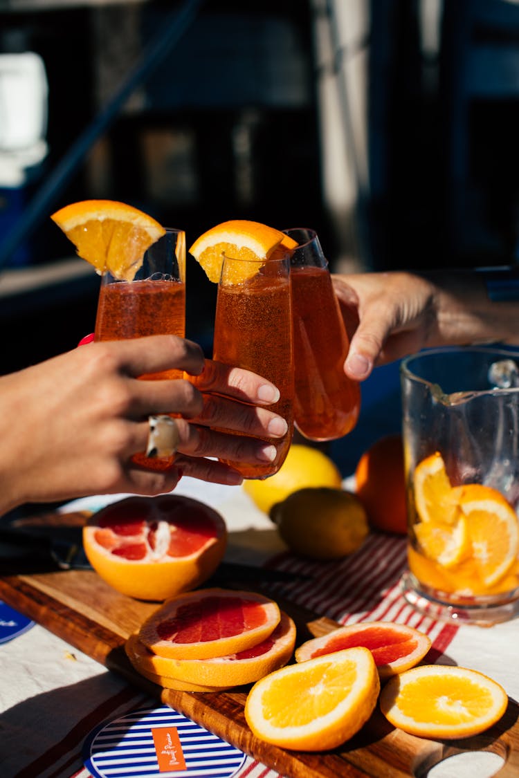 Crop People Drinking Cocktails With Orange