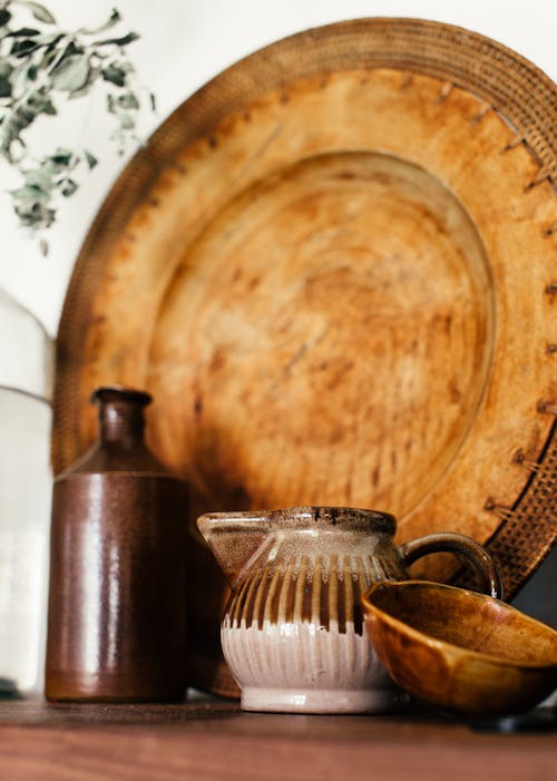 Old vintage ceramic teapot and bowl with bottle on wooden shelf against aged wooden tray