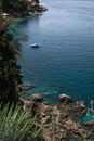 沿着岩石海岸，清澈的蓝色海水中有一艘船，海景宁静