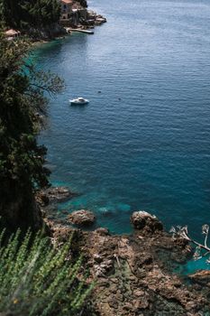 沿着岩石海岸，清澈的蓝色海水中有一艘船，海景宁静