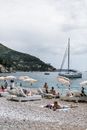 Sandy beach on seashore full of sunbathing people resting on sunbeds with parasols