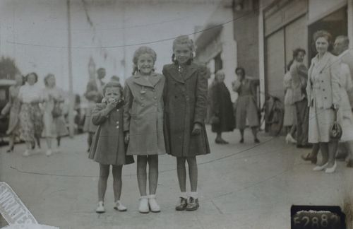 Free Charming vintage image shows three young girls smiling on a bustling street, evoking nostalgia and family memories. Stock Photo