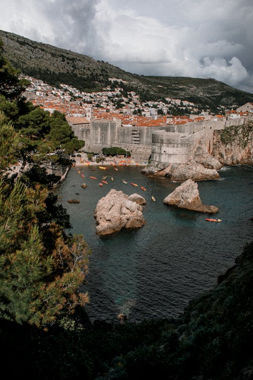 From above of old stone castle on green mount near nautical transport on rippled sea under cloudy sky in Croatia