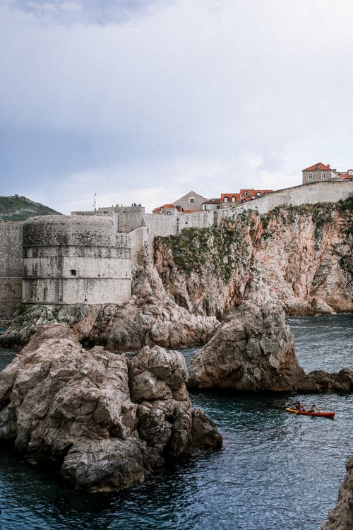 Free Scenery view of aged stone fortress on mountain near rippled Adriatic Sea with boat in Dubrovnik Stock Photo